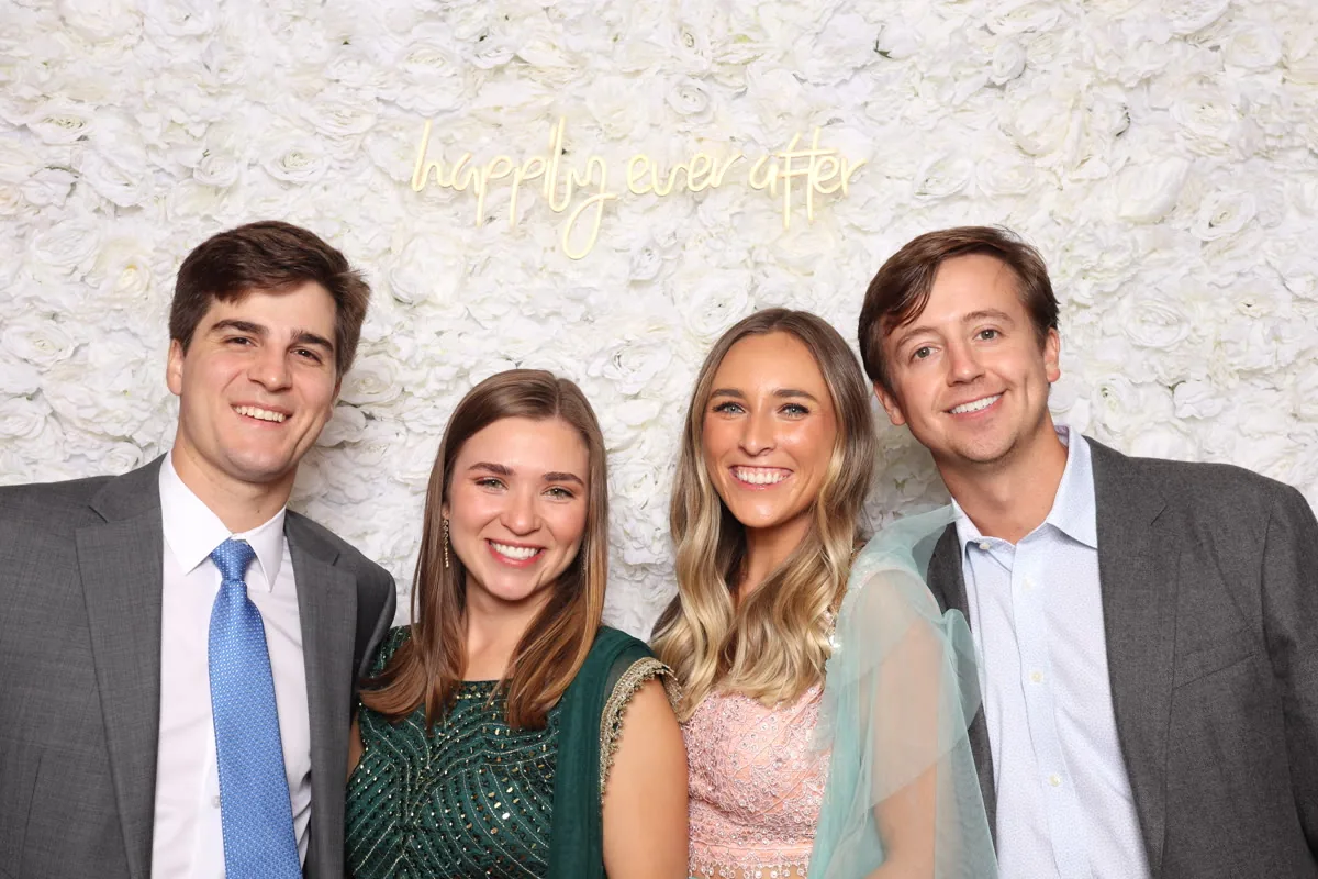 Clutch City luxury photo booth with floral wall and neon sign at Houston wedding
